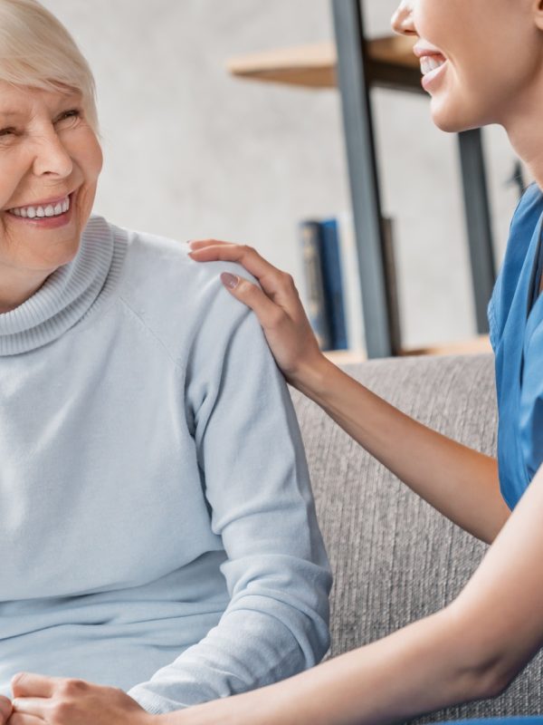 Friendly asian assistant caring senior woman home in living room