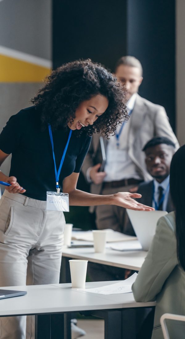 Surprised African female business mentor talking to audience and gesturing during a conference